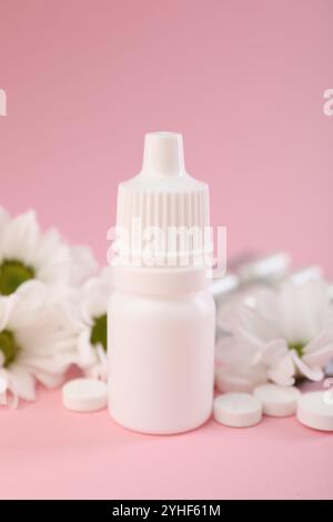 Allergiebehandlung. Nasentropfen, Pillen und Blumen auf rosa Hintergrund, Nahaufnahme Stockfoto