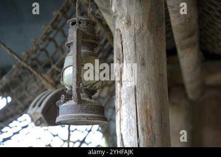 Weathered Glow: Staubige, rostige Laterne, die in einer Holzhütte hängt Stockfoto