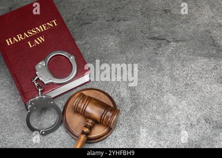 Belästigungsgesetzbuch, richterlicher Hammer und Handschellen auf dem grauen Tisch, über dem Bild Stockfoto
