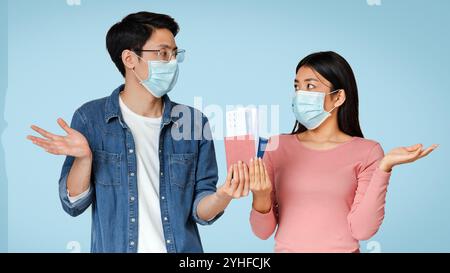 Verwirrte Asiatische Paare In Medical Masks Holding Passport Und Tickets Stockfoto