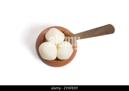 Blick von oben auf die traditionelle indische Rasgulla, serviert in einem Tontopf mit einem Holzlöffel auf weißem Hintergrund. Perfekt für festliche indische Anlässe. Stockfoto