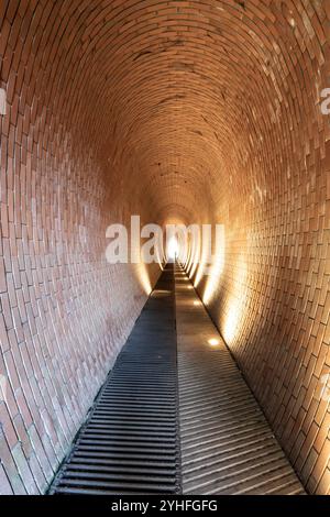 Der Fußgängertunnel des Hirschgräbens in der Nähe der Prager Burg ist ein einzigartiges Backsteindesign, das Besucher auf ihrer Reise zu einem Spaziergang durch den beleuchteten Pfad einlädt. Stockfoto