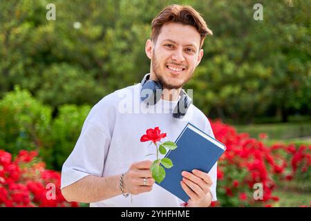 Porträt eines jungen Latinos in einem Park mit einem Buch und einer Rose Stockfoto