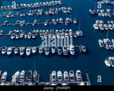 Blick aus der Vogelperspektive auf zahlreiche Boote und Yachten, die tagsüber in einem geschäftigen Yachthafen angedockt sind Stockfoto