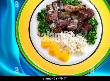 Die beste und traditionellste brasilianische Feijoada der Welt, serviert auf einem grünen und gelben Teller Stockfoto