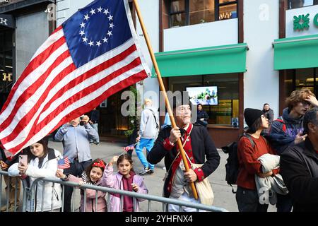 Während der Veterans Day Parade auf der Fifth Avenue in New York am 11. November 2024 schwingt ein historischer Reenactor eine Flagge mit den ursprünglichen Kolonien. (Foto: Gordon Donovan) Stockfoto
