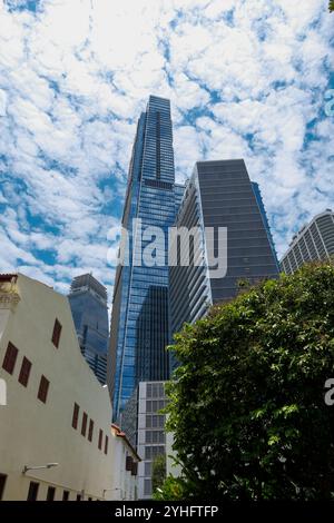 Ein Blick auf den Guoco Tower Singapur, der die kleineren Ladenhäuser in den Schatten stellt und gleichzeitig den Kontrast der Architektur innerhalb der Stadt zeigt. Stockfoto