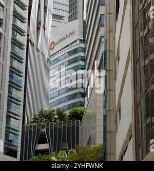 Das Bürogebäude der Bank of Singapore wurde auf einem Teleobjektiv aufgenommen, das von den umliegenden Wolkenkratzern und dem Wohngebäude von Capitaspring eingerahmt wird. Stockfoto