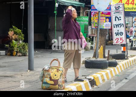 BANGKOK, THAILAND, 09. März 2024, eine ältere Frau mit Gepäck wartet auf die Straße Stockfoto