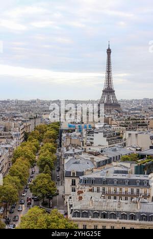 Panoramablick auf Paris mit dem in der Ferne stehenden Eiffelturm, umgeben von den Dächern und von Bäumen gesäumten Alleen der Stadt. Stockfoto