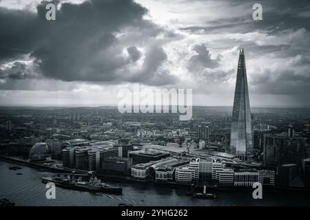 Der Shard überragt die Skyline Londons, dessen scharfes Design im Kontrast zur weitläufigen Stadt unter sich steht, mit dramatischen Wolken am Himmel. Stockfoto