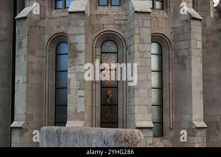 Eine Nahansicht der Buntglasfenster an einer Kirchenfassade mit komplizierten Mustern, die sich auf der Oberfläche des Gebäudes widerspiegeln. Stockfoto