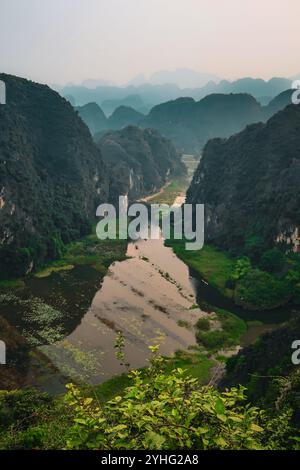 Blick auf den malerischen Fluss von Tam Coc, der sich durch üppige Kalksteinklippen schlängelt und eine ruhige und malerische Landschaft in Ninh Binh, Vietnam, schafft. Stockfoto