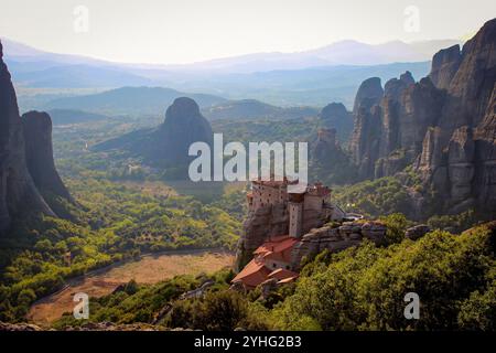 Ein atemberaubender Blick auf die Meteora-Klöster in Griechenland, eingebettet auf Klippen inmitten grüner Täler und zerklüfteter Felsformationen unter hellem Himmel. Stockfoto