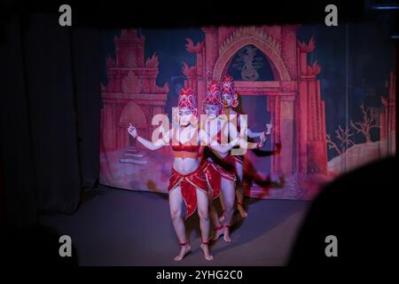 Drei Tänzer in komplizierten roten Kostümen treten im Einklang auf und heben den traditionellen vietnamesischen Tanz vor einem Tempelmotiv in Hoi an hervor. Stockfoto