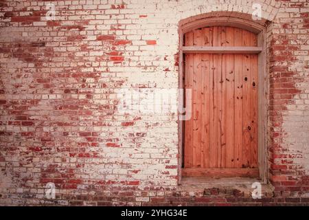 Frisch verschlossenes Fenster in der Wand mit abblätternder Farbe auf alten Ziegeln Stockfoto