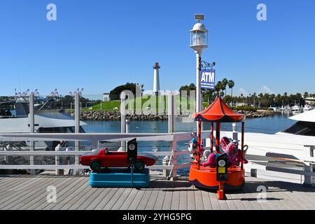LONG BEACH, KALIFORNIEN - 8. November 2024: Münzfahrten im Shoreline Village mit dem Lions Lighthouse im Hintergrund. Stockfoto