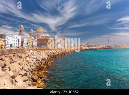 Malerischer Blick auf die Kathedrale von Cadiz entlang der Uferpromenade in Cadiz, Spanien, mit ihrer goldenen Kuppel und den umliegenden historischen Gebäuden entlang der Küste. Stockfoto