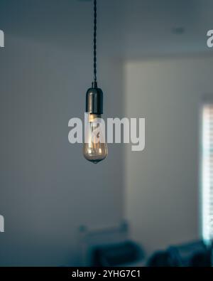 Dieses hochwertige Bild verfügt über eine gelbe LED-Leuchte, die einen Vintage-Stil nachahmt. Die Lampe hängt an der Decke und zeigt ihre Stockfoto