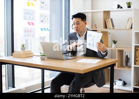 Asiatischer Geschäftsmann mit Headset führt Online-Präsentationen mit Diagrammen durch Stockfoto