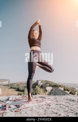 Frau übt Yoga in Baumstellung auf einem Berggipfel Stockfoto