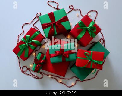 Geschenkset auf weißem Hintergrund. Traditionelle Weihnachtsrot- und -grüne Farben. Boxen in verschiedenen Größen. Mit Bändern und Schleifen gebunden. Um eine Girlande Stockfoto