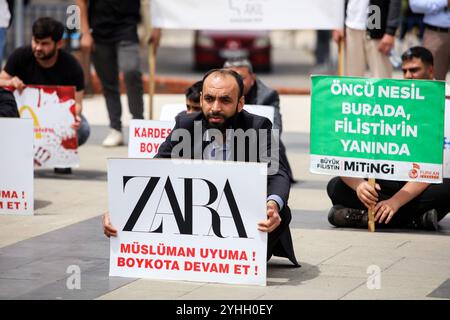 Gaziantep, Turkiye. Mai 2024. Universitätsstudenten in Gaziantep halten eine Solidaritätsdemonstration mit Palästinensern in Gaza ab und verurteilen gleichzeitig die laufende israelische Militäroffensive in der Küstenenklave. Die Teilnehmer schwenkten die palästinensische Flagge, warfen Banner, die westliche Unternehmen, die Israel unterstützen, verurteilten, und zeigten auch Unterstützung für pro-palästinensische Demonstranten auf College-Campus in den Vereinigten Staaten. Umhüllte Babymodelle wurden mit Blumen auf den Boden gelegt, um die große Zahl der in Gaza getöteten Kinder zu betrauern Stockfoto
