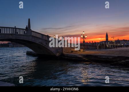 Ruhiger Abend in der Stadt Venedig in Italien. Kanal Rio dell’Arsenal mit Brücke Ponte San Biasio delle Catene, die in die Lagune von Venedig eindringt. Stockfoto