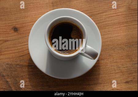 Genießen Sie einen Moment der Ruhe mit einer frisch gebrühten Tasse Kaffee auf einem warmen Holztisch. Stockfoto