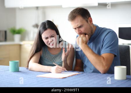 Ein wütendes Paar, das zu Hause in der Küche einen schlechten Papiervertrag überprüft Stockfoto