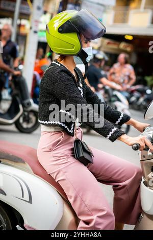 Eine junge Thai-Dame, die auf einem Motorrad oder Roller saß, macht sich den Weg entlang Soi Buakhao, Pattaya City, Thailand. Stockfoto