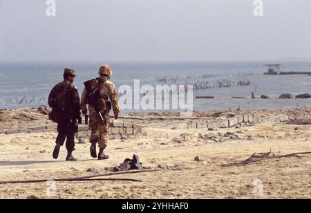 Erster Golfkrieg: 10. März 1991 amerikanische Soldaten am Anjafa Beach in Kuwait City: In Erwartung der Invasion der Koalitionstruppen vom Meer aus wurden rudimentäre Verteidigungsanlagen von der irakischen Armee errichtet. Stacheldraht und Abwehrvorrichtungen für Landefahrzeuge wurden in der Untiefen nahe des Ufers aufgereiht. Auch die Strände wurden abgebaut. Stockfoto