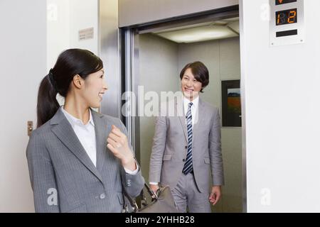 Anzug Frau und Geschäftsmann reden vor dem Aufzug Stockfoto