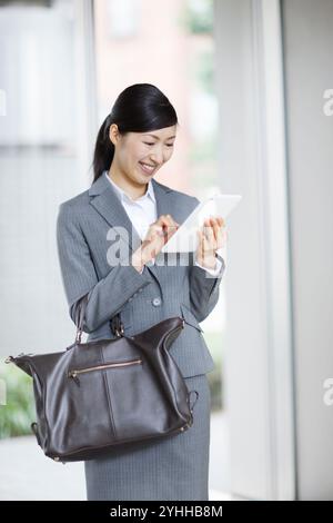 Frau im Anzug, die auf dem Tablet sucht Stockfoto