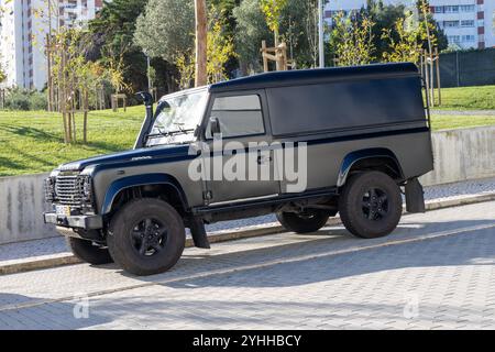 Maßgeschneiderter schwarzer Land rover Defender, der in der Nähe eines Parks in einer städtischen Umgebung parkt Stockfoto