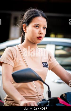 Ein wunderschönes junges Thai-Mädchen, das auf einem Motorrad oder Roller saß, macht sich den Weg entlang Soi Buakhao, Pattaya City, Thailand. Stockfoto