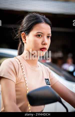 Ein wunderschönes junges Thai-Mädchen, das auf einem Motorrad oder Roller saß, macht sich den Weg entlang Soi Buakhao, Pattaya City, Thailand. Stockfoto