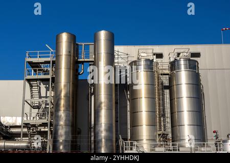 Metallsilos und Rohre dominieren die Skyline einer modernen industriellen Verarbeitungsanlage und zeigen die Größenordnung des Betriebs vor einem klaren blauen Himmel Stockfoto