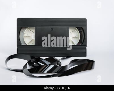 Videokassette mit chaotisch abgewickeltem Magnetband im Vordergrund isoliert auf weißem Hintergrund. Stockfoto