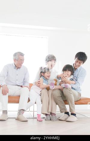 Großvater, Großmutter, Sohn und zwei Enkelinnen sitzen auf dem Sofa Stockfoto