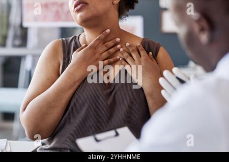 Abgeschnittener Schuss von erwachsener afroamerikanischer Frau, die mit dem Arzt während der Konsultation in der Klinik spricht und Hautausschlag am Hals demonstriert, der Allergiesymptome erklärt, Kopierraum Stockfoto