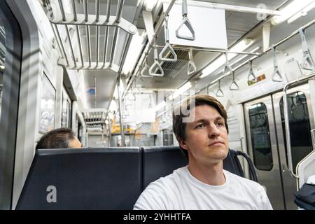 Mann sitzt ruhig in einer fast leeren U-Bahn während der frühen Morgenstunden Stockfoto