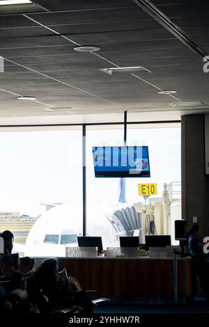 Abflug an einem Flughafenterminal mit Blick auf den Jet und die Abflugzeit auf dem Bildschirm Stockfoto