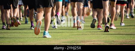 Laufsportler laufen in einem Laufrennen, laufen auf Rasendetails an den Beinen, laufen im Licht des morgens. Eine große Gruppe von Angusskanälen Stockfoto