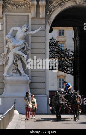 Touristen und Pferdekutsche unter der Skulptur von Herkules und Antaeus. Flügel der Reichskanzlei im Hof der Hofburg. Wien Stockfoto