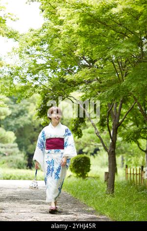 Frau in Yukata, die im japanischen Garten läuft Stockfoto