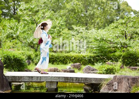 Frau in Yukata, die im japanischen Garten läuft Stockfoto