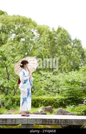 Frau in Yukata, die im japanischen Garten läuft Stockfoto