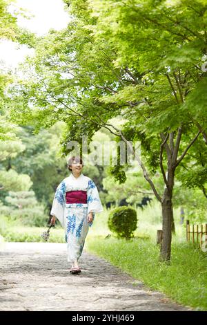 Frau in Yukata, die im japanischen Garten läuft Stockfoto