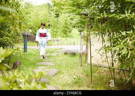 Frau in Yukata, die im japanischen Garten läuft Stockfoto